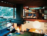 Architect Ray Kappe, who died in 2019, sits at the central hearth on the north end of the comfortable sunken living area at his home in Los Angeles. From this perspective, you can see how the interior spaces flow into one another, passing one half-level up into the breakfast nook and kitchen and out from there onto the overgrown hillside. The various built-in furnishings have all been there since the house's construction.
