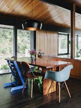 An assortment of dining chairs, including vintage iterations on the Eames shell chair by Charles and Ray Eames and Stokke's Tripp Trapp chair, are clustered around a table lit by a pendant lamp by Coco Flip Design Studio.